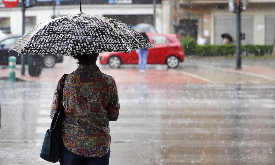 Una mujer se protege bajo la lluvia .EFE/Kai Forsterling